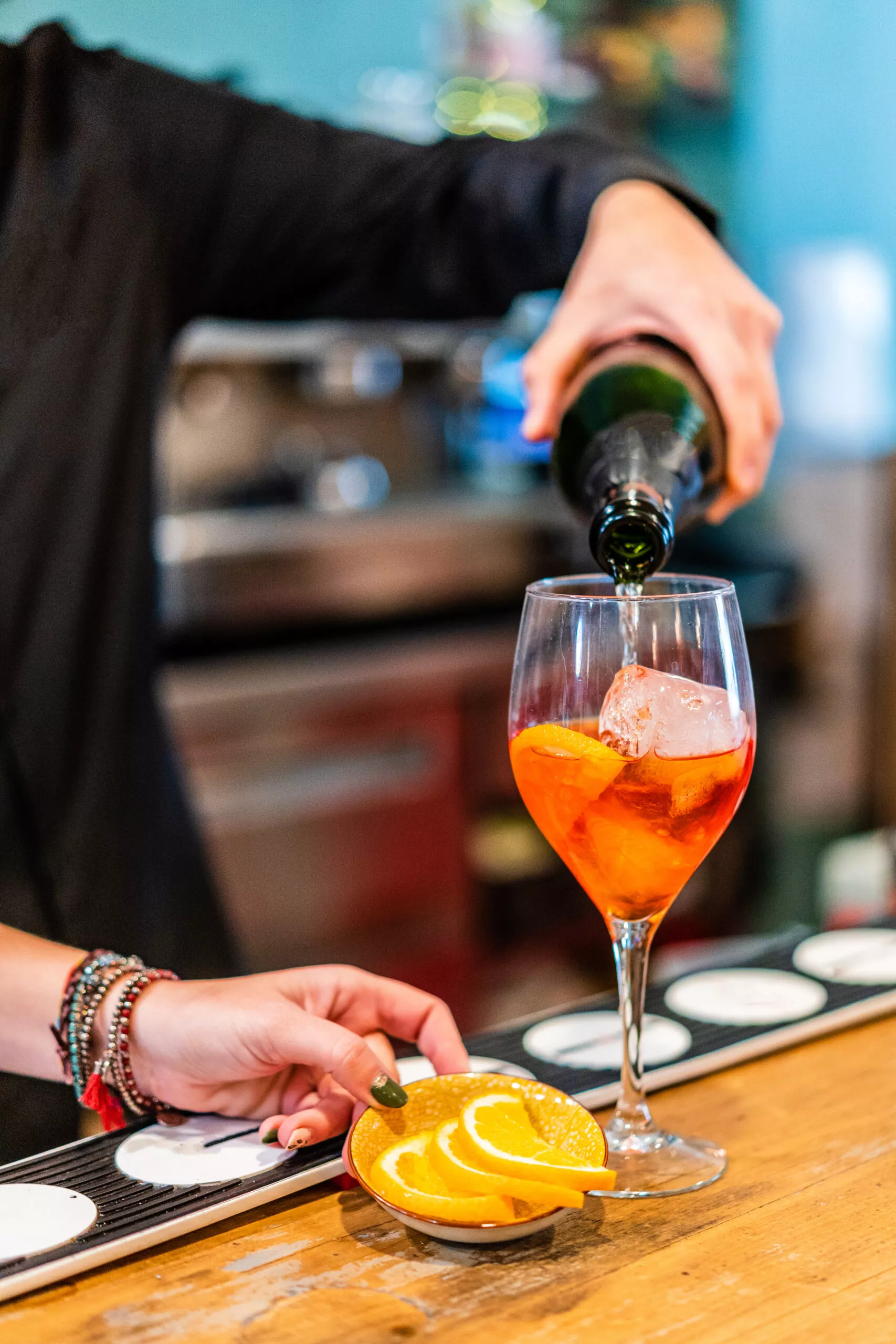 bartender serving orange cocktail with citrus slices decorating the glass