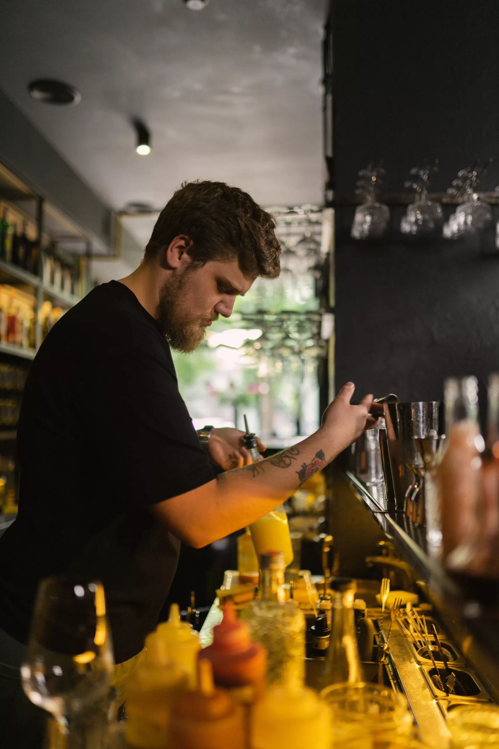 Barman manipuleert met ingrediënten om cocktail te maken voor klant. Masterclass in het maken van ambachtelijke drankjes door professionele barman