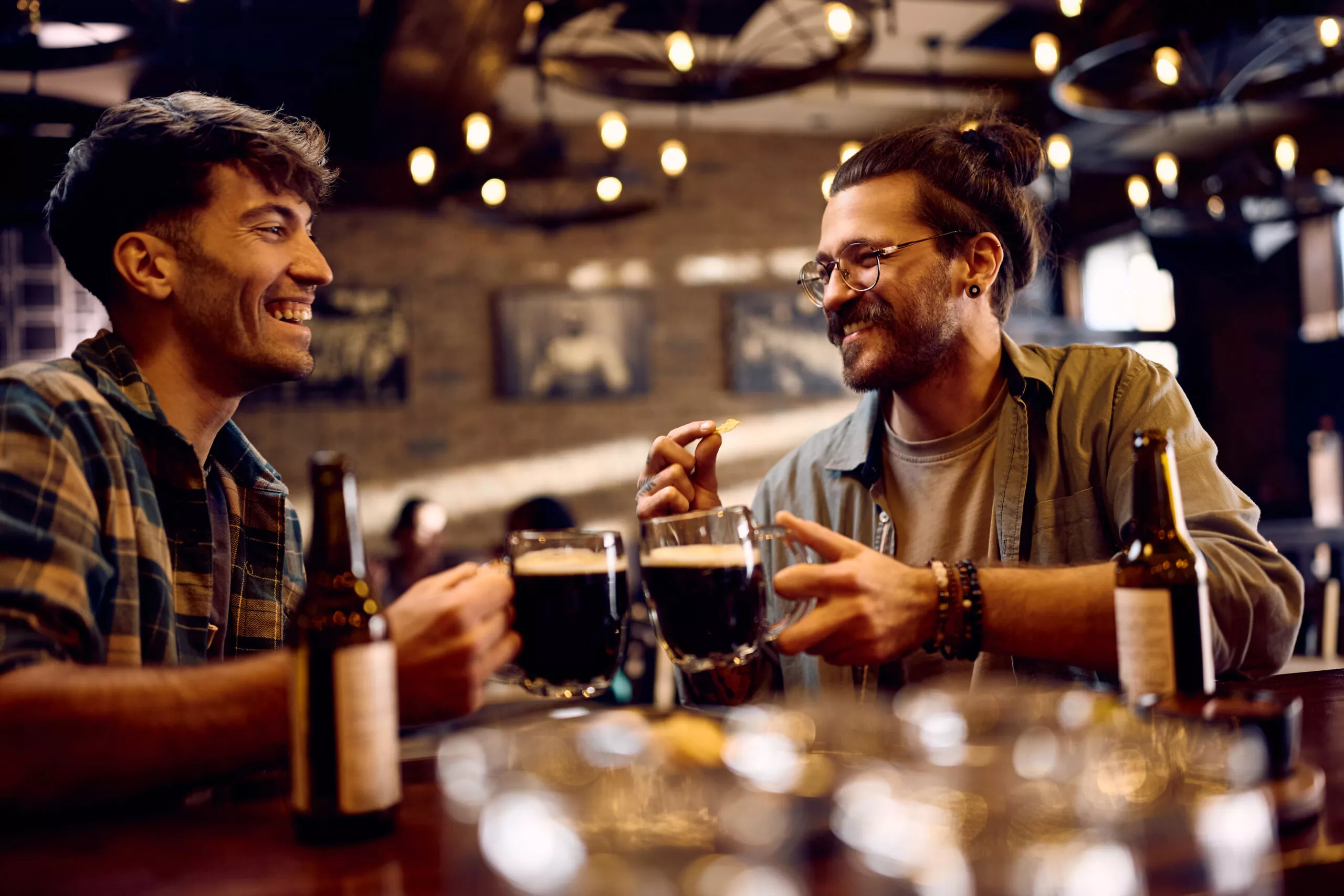 Uomini felici che brindano bevendo birra in un pub.