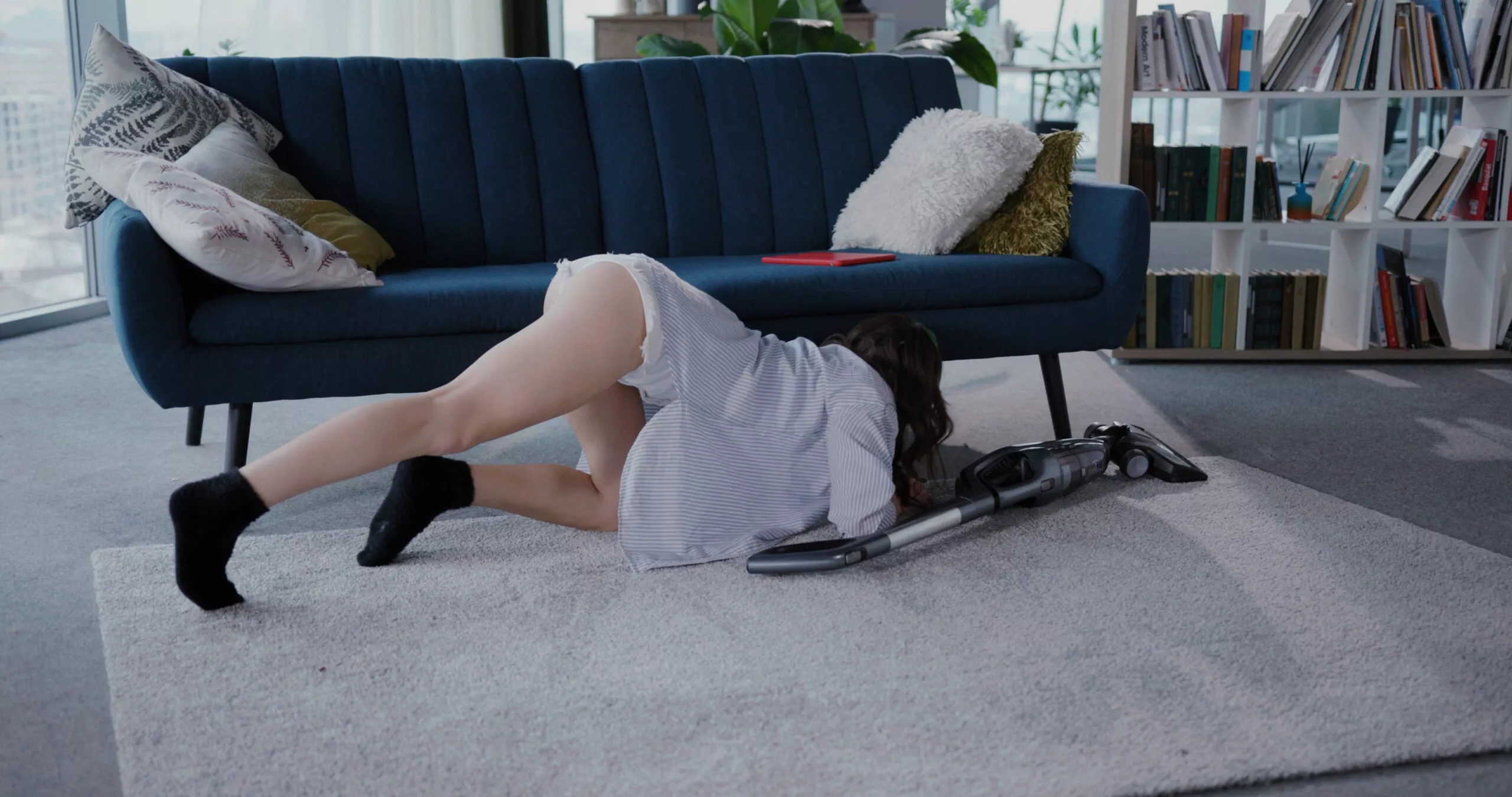 Charmante sexy junge attraktive Frau in weißem Freizeitoutfit sitzt auf dem Boden Reinigung Staub mit Staubsauger. Hausfrau. Vergnügen.