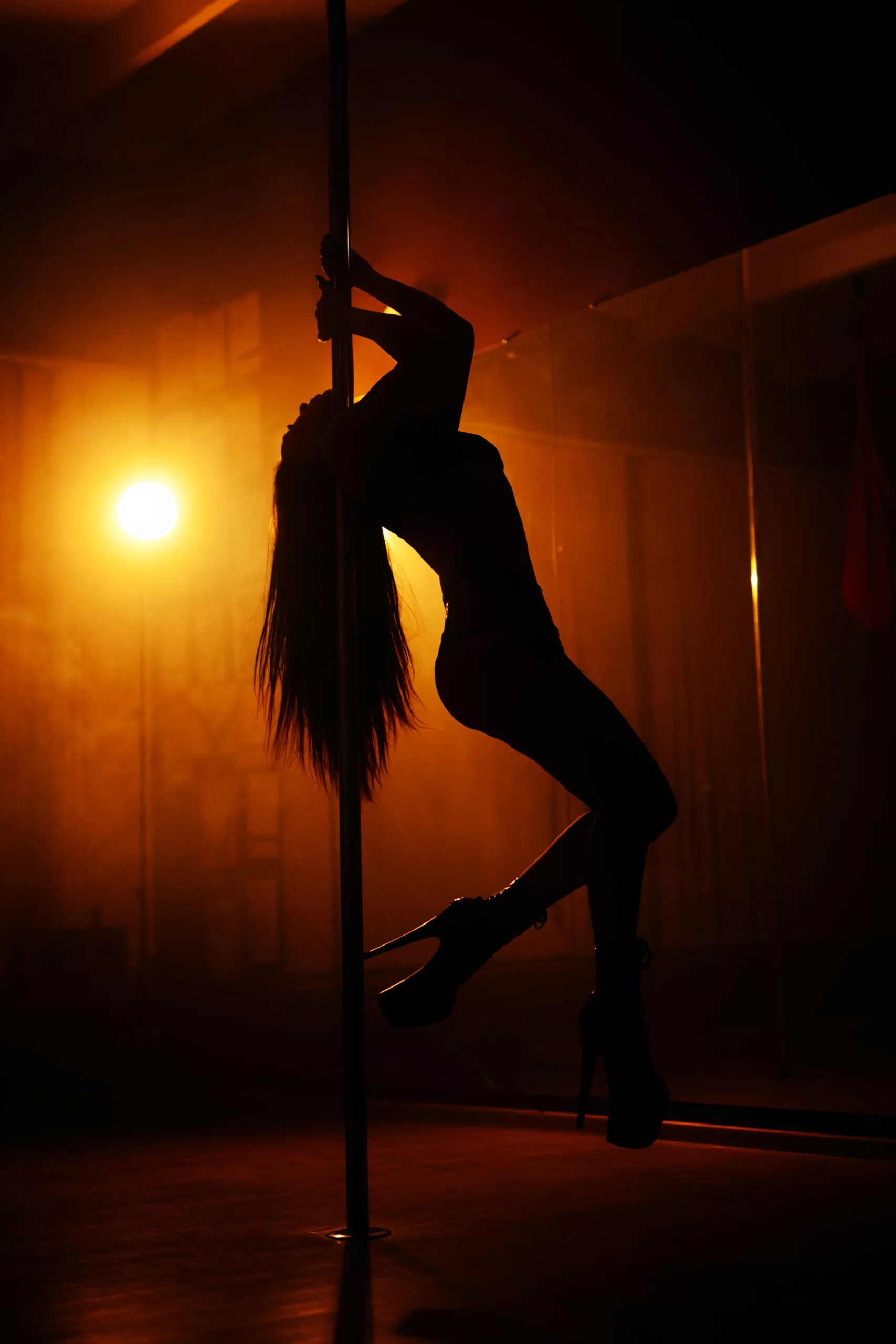 Silhouette eines Mädchens auf einem Hintergrund von Licht, das Striptease tanzt